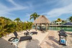 Backyard is vacation ready with a Tiki Hut, water views, lounge chairs